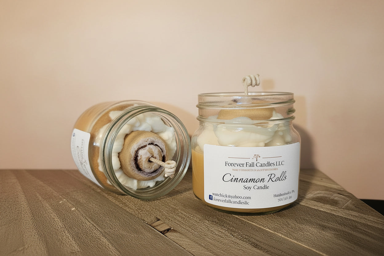 Candle in a glass jar labeled 'Cinnamon Rolls' by Forever Fall Candles LLC on a wooden surface.